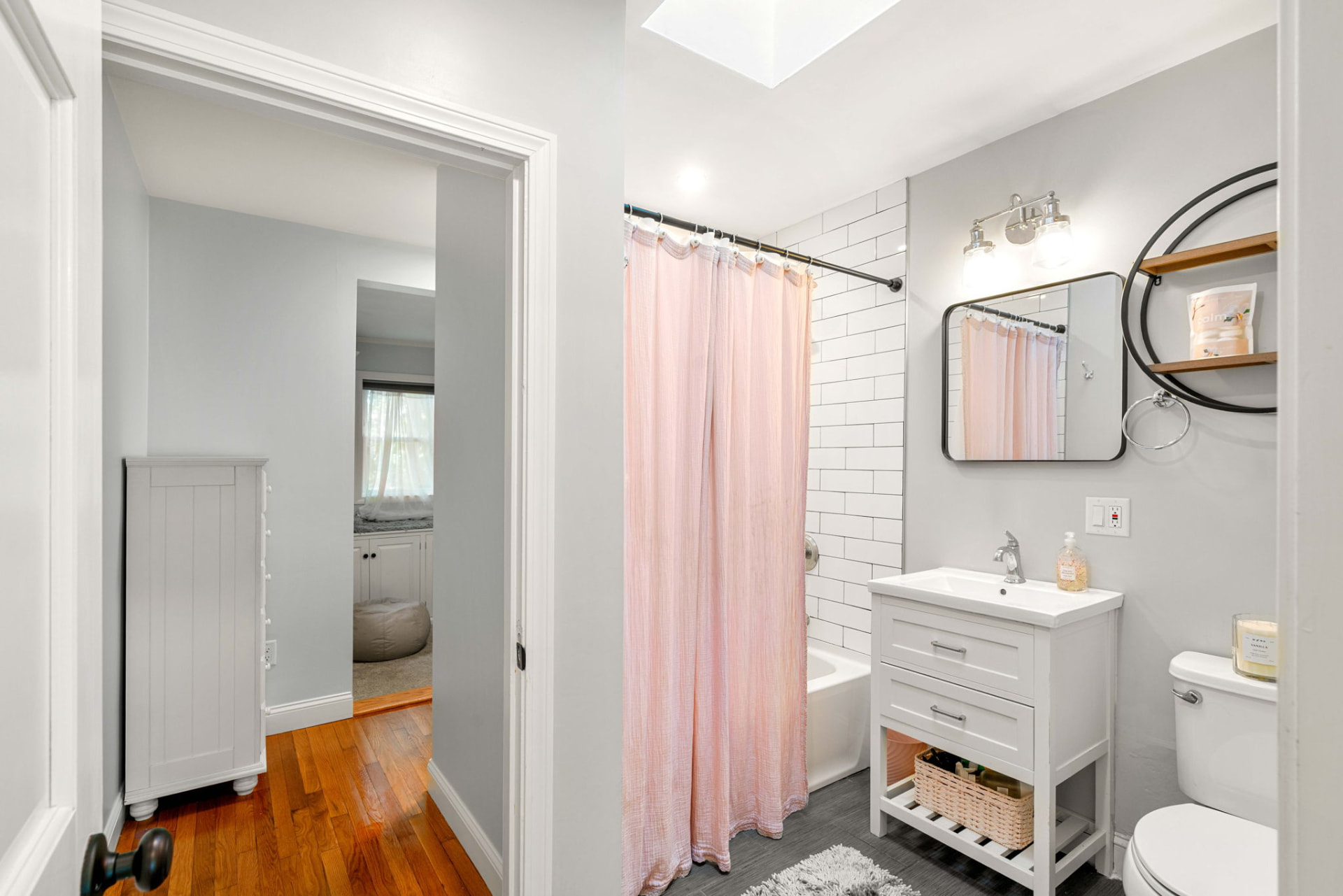 Bath and bedroom hallway with hardwood floors and skylight