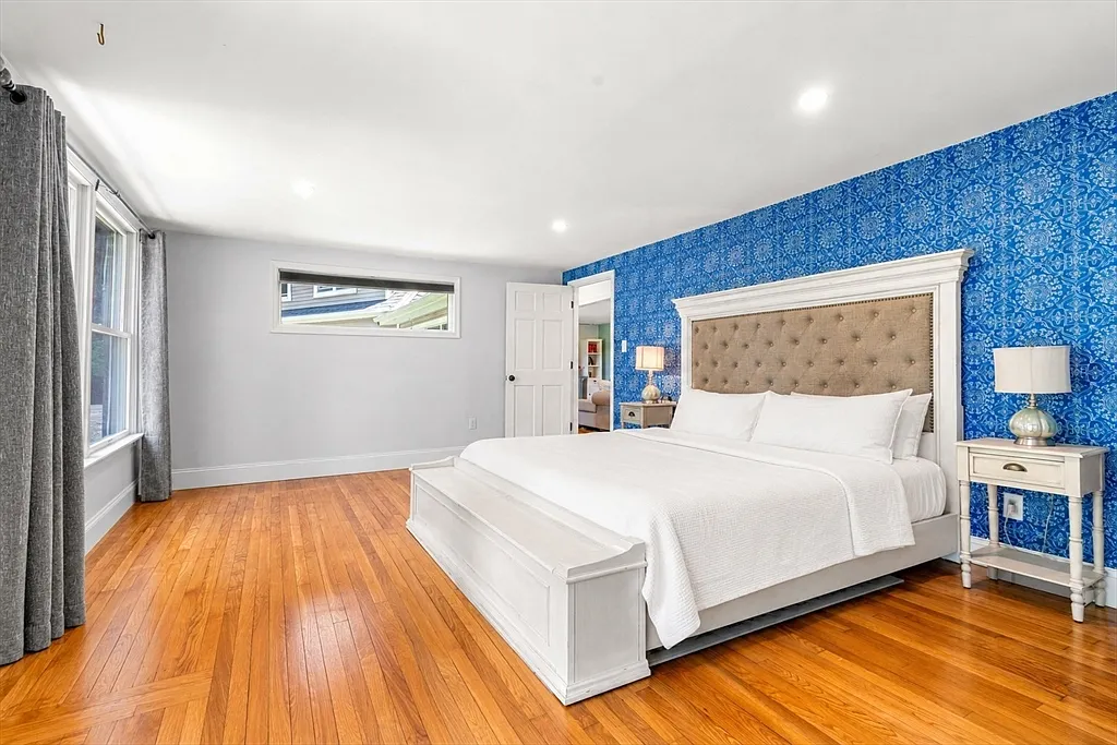 Primary bedroom with king bed, hardwood floors, and patterned accent wall